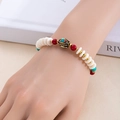 Vue détaillée d'un bracelet bohème perlé avec breloque œil en émail porté au poignet - Richesse Prospère