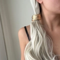 Close-up of a minimalist gold metal hair ring worn on a sleek ponytail by a model - Textured Arc Style / Gold