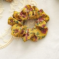 Detailed view of ginger floral scrunchie with red flower patterns on linen background - Ginger Yellow