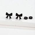 Macro shot of matte black bow-knot earrings on a white stone surface showing fine details - 105 Bow / Black