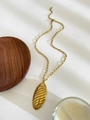 Macro detail of golden metal hollow oval pendant with striped texture on a chain - Striped Oval Pendant / Gold Leaf