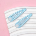 Detail showing two blue painted metal water drop hair clips on a wavy white prop - Blue