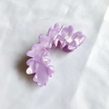 Detalle de pinza para el pelo ondulada morada con brillo perlado en tela blanca con textura - 8.5cm / Morado