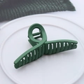 Detail of dark green matte hair claw clip on white tray showing anti-slip teeth and texture - Matte Cross Army Green