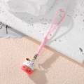 Detail of white Lucky Cat charm with red accents and pink strap on textured stone - Pink Blessing