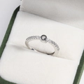Close-up of a silver letter G ring with clear crystals in a green velvet jewelry box - Platinum Q