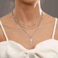 Three-layer silver cross necklace set with pearls worn by a model on a gray background - Silver Triple Layer Cross Pearl Necklace
