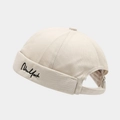 Detail of beige brimless cap featuring black New York cursive embroidery and adjustable buckle - Adjustable / Beige