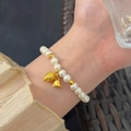 Elegant pearl beaded bracelet with golden flower pendant shown on wrist for women - Gold Flower Bud Bell Pearl (MY37807)