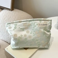 Light green floral jacquard makeup bag with A GOGO ORIGINAL tag on white desk - Light Green Cherry Blossom