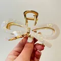 Close-up of golden bow hair claw with pearlescent acetate finish and metal spring - 11.5cm Claw Clip / Fairy White