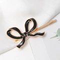 Detalle de una pinza para el pelo con lazo de esmalte negro y bordes dorados - Negro