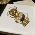 Primer plano del broche de oso dorado con cristales brillantes sobre joyero blanco con textura - Panda Dorado