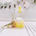 Detail of acrylic milk tea keychain with white seal figure, liquid, and golden clasp - Yellow (Milk Tea Spotted Seal)