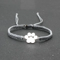 Detail view of a handmade gray braided cord bracelet with a silver dog paw charm - Gray