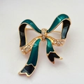 Vue macro d'une broche nœud vintage en émail vert foncé et strass brillants dorés - Style Noeud Papillon (A)