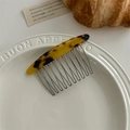Close-up of tortoiseshell patterned acetate hair comb with metal teeth on a ceramic plate - Dark Leopard Print