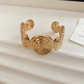 Détail macro du bracelet manchette à motif spirale doré avec finition miroir poli - Doré