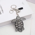 Detail of turtle keychain featuring black tassels and shimmering crystal rhinestones - Black
