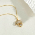 Detailed close-up of a golden mushroom pendant with white pavé zircons and a heart charm - Jellyfish