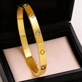 Close-up of a gold-plated stainless steel bangle featuring clover motifs and zircons - Gold
