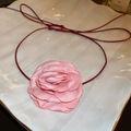 Collana con fiore di stoffa rosa e cordino rosso esposta su un piatto di ceramica bianca - Rosa
