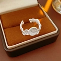 Detalle de un anillo plateado ovalado con textura dentro de un joyero de terciopelo suave - Blanco