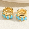 Detail of gold ear cuffs featuring oval blue stones with a textured metal finish - Gold Triple Layer Turquoise Blue Zircon Ear Cuff