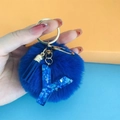 Detailed view of blue pompom and resin letter Y keychain with gold hardware - Letter Y