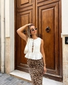 Detalle de blusa blanca sin mangas con lazo y falda midi de leopardo en modelo real - S / Top Blanco