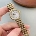 Close-up of golden chain strap watch with elegant white mother-of-pearl dial texture - Gold