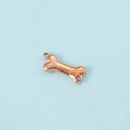 Detail of rose gold bone pendant with pink zircon inlay on a clean blue background - Rose Gold October