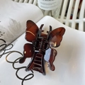 Detailed view of amber butterfly hair claw clip with glossy finish on a white magazine - Butterfly Buckle Style / Approx 11cm / Glossy Red Brown