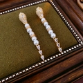 Detail von eleganten Gold-Ohrhängern mit weißen Perlen und Tropfenkristallen auf Samt - Roségoud Hart Parel Stijl (925 Sterling Silber Earring Post)