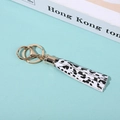 Detail of PU leather tassel keychain with black and white spots and golden metal clasp - Spotted White
