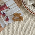 Detail of an amber acrylic hair claw clip placed on a woven mat with aesthetic background - Dark Tea