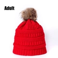 Close-up of red knit beanie with faux fur pom-pom and thick ribbed texture for adults - Red