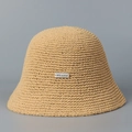 Detail of hand-woven straw bucket hat featuring a silver metal brand name tag - M (56-58cm) / Khaki