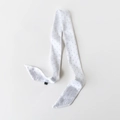 Detail eines weißen Satin-Twilly-Schals mit schwarzen Punkten und weichem Pflegeetikett - Weiß