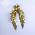 Close-up of golden sequined scrunchie with long ribbons on white background - Gold