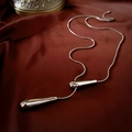 Detalle de cadena de serpiente plateada con colgante de gota sobre terciopelo - Plateado