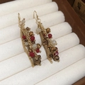 Macro shot of gold chain fringe earrings with red and white crystal beads in a box - Tassel Beaded Style