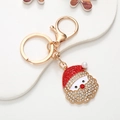 Close-up of Santa Claus keychain with red rhinestones and a white pearl on a tray - Santa Claus B Style (Gold) (D2844)