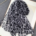 Chic leopard print voile scarf in grey and black tones shown flat on a minimal background - Gray