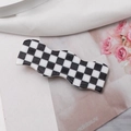 Close-up of a wave-shaped black and white checkerboard hair clip on floral background - Black and White Small Plaid
