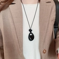 Gros plan d'un collier pendentif goutte noir porté par un mannequin en blazer - 59# Collier-Noir