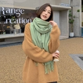 Elegant green soft tassel wool scarf worn by a model in a cozy outdoor cafe setting - Dark Fruit Green