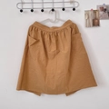 Detail of ginger yellow cotton apron with large pockets and elastic waist on wall - Apricot Yellow