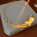Detalle macro del colgante de torso femenino dorado en cadena de eslabones ovales - Collar - Dorado