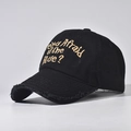 Close-up of golden embroidery and distressed brim details on a black cotton baseball cap - Adjustable / Black